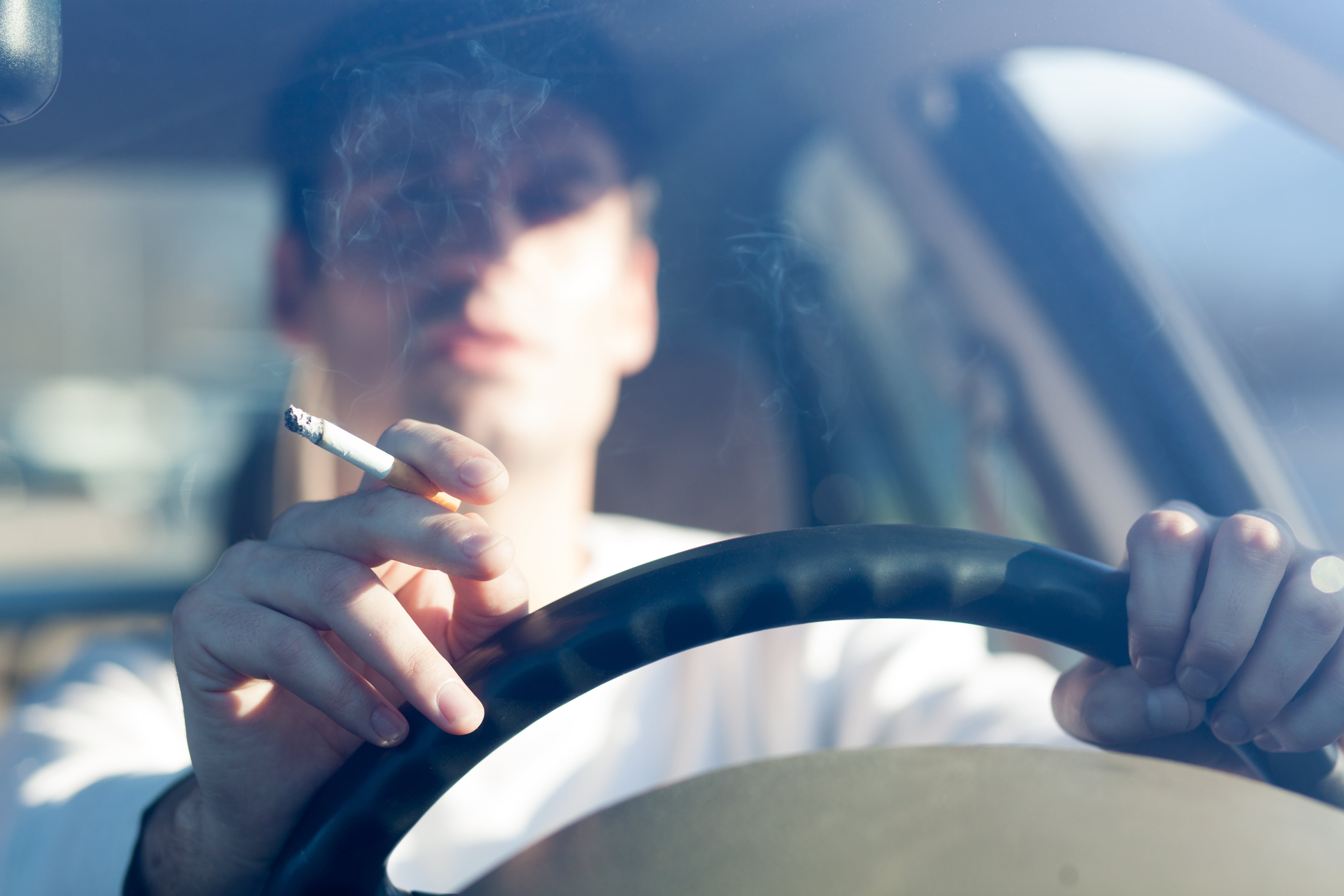 Una persona fumando en su vehículo.