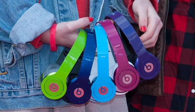 Una joven sostiene varios auriculares Beats