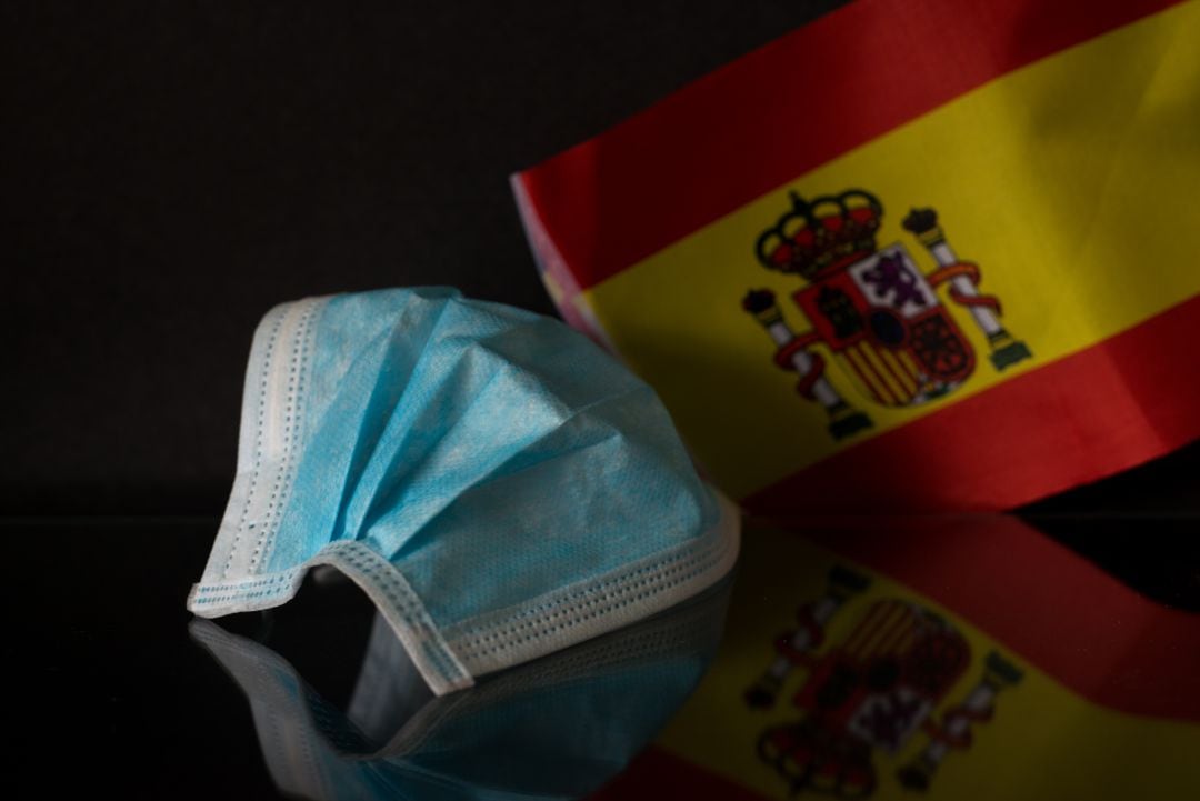 Imagen de archivo de una mascarilla quirúrgica y una bandera de España.