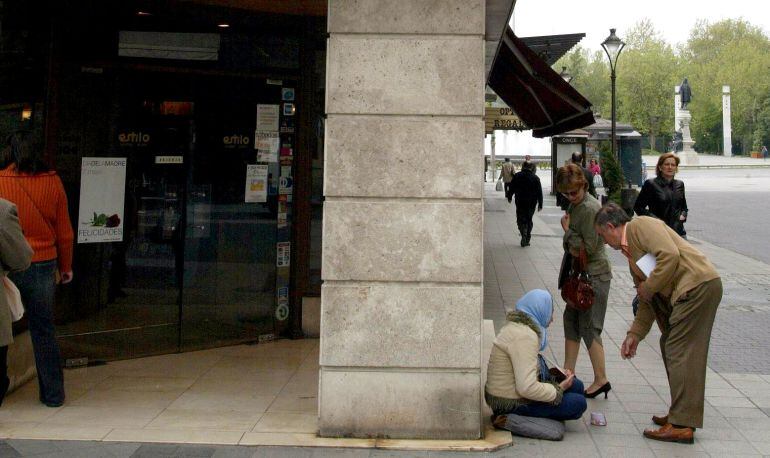 Una mendiga recibe una limosna en la calle Santiago de Valladolid