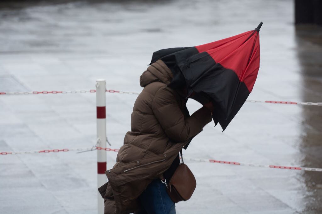 Una mujer se protege de la lluvia y del viento.