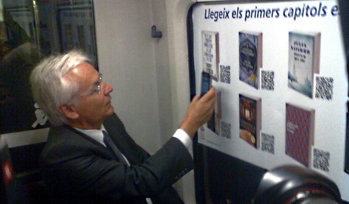 El conseller de Cultura, Ferran Mascarell, prova el sistema de descàrrega de llibres amb codi QR a un vagó dels Ferrocarrils de la Generalitat