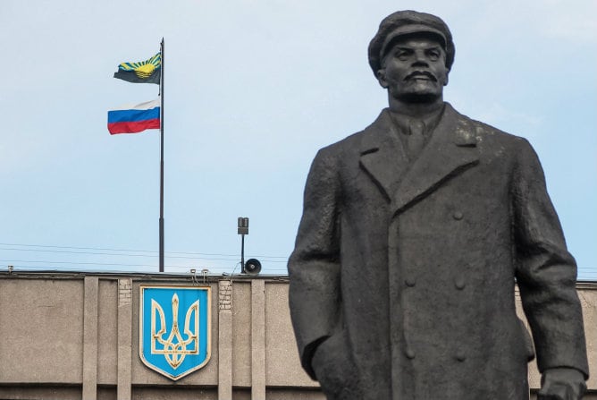 Vista de una bandera rusa y la bandera de la región de Donetsk detrás de la estatua de Lenin en un edificio administrativo público ocupado por manifestantes