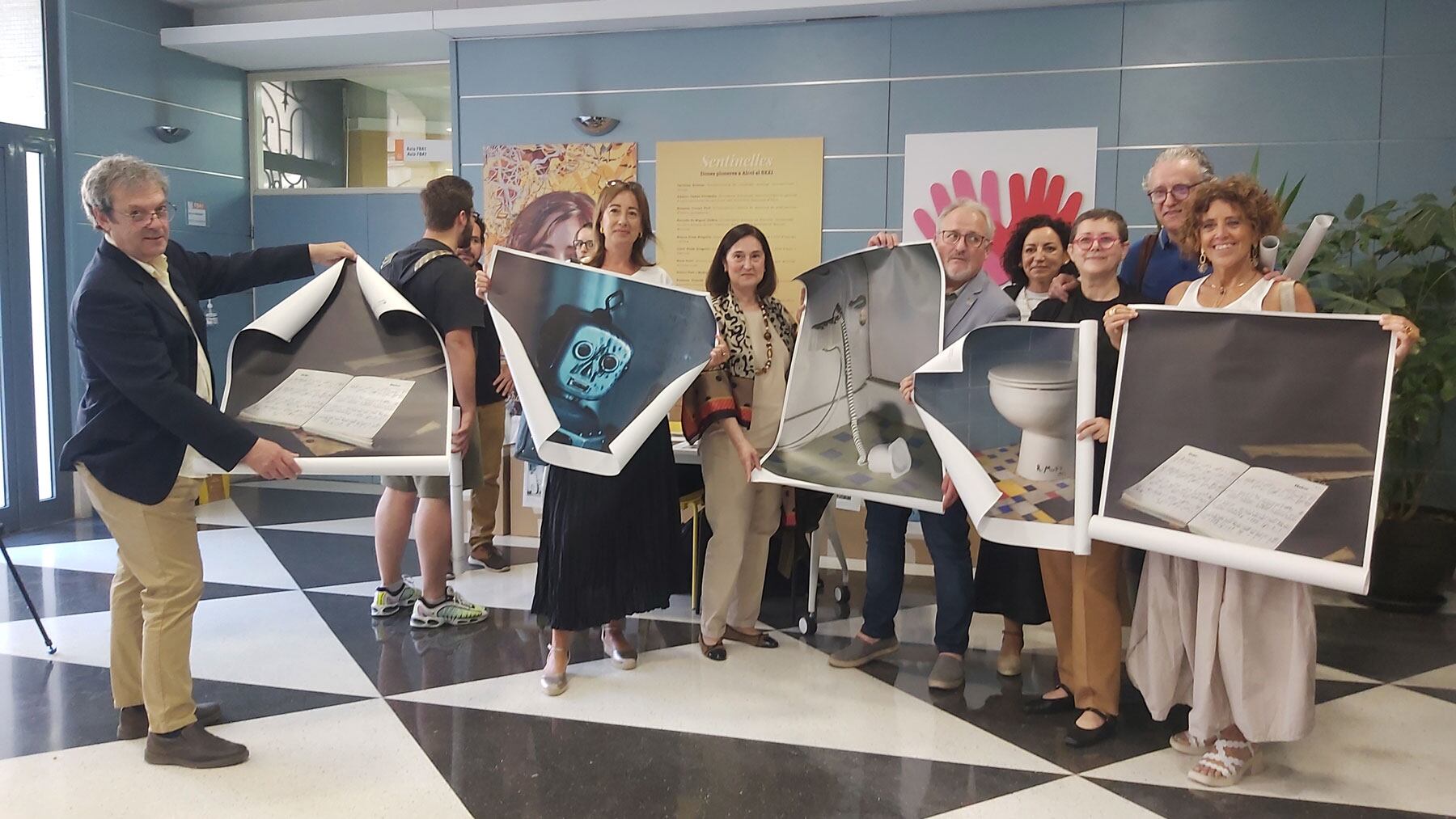 Los asistentes a la inauguración de la exposición con ejemplares de las fotos de Cristina de Middel en formato póster