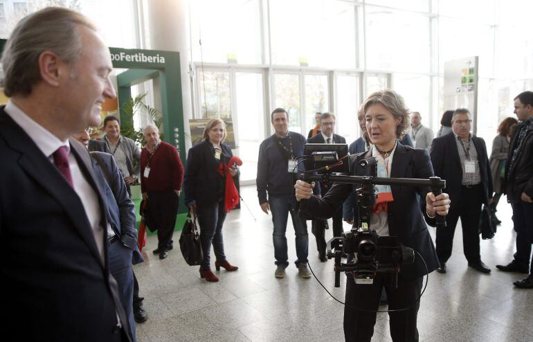 La ministra de Agricultura, Isabel García Tejerina, prueba una cámara con estabilizador en presencia del president de la Generalitat, Alberto Fabra (i), durante el VII Congreso nacional de cooperativismo alimentario