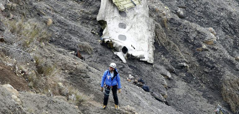 HOR111 LE VERNET (FRANCIA), 25/03/2015.- Un miembro de los servicios de rescate camina al lado del mayor un tramo de fuselaje del avión siniestrado, en el que se aprecian tres ventanillas, entre millones de fragmentos del aparato esparcidas por una amplia