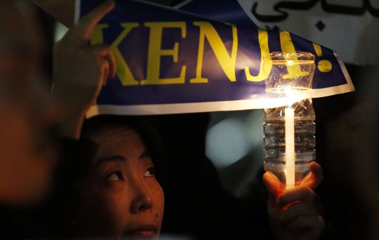 A woman holding a candle and placard takes part in a vigil in front of Prime Minister Shinzo Abe&#039;s official residence in Tokyo, January 30, 2015. Japan and Jordan were working closely on Friday to find out what had happened to two of their nationals being