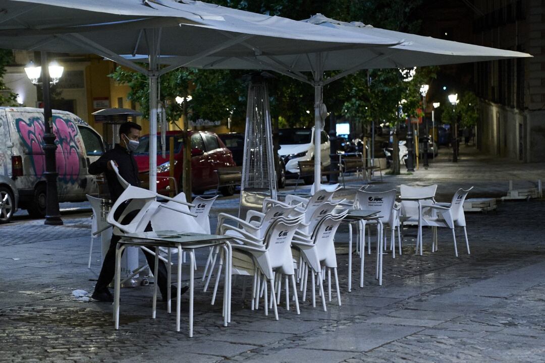 Un camarero recoge la terraza de una cafetería en Madrid.