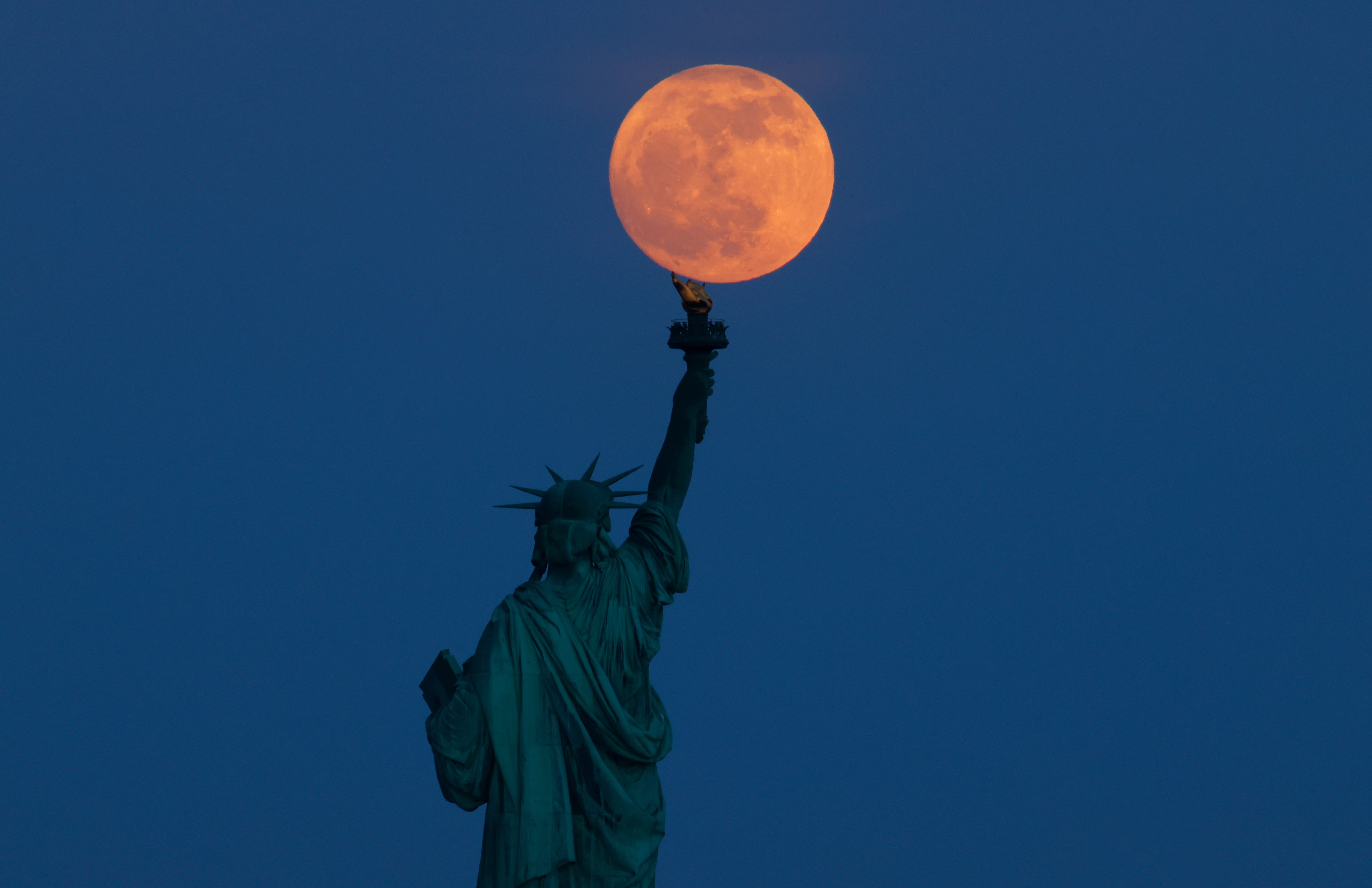 La luna llena de mayo, también conocida como &#039;Luna de las flores&#039;, sobre la Estatua de la Libertad de Nueva York, en una vista desde Nueva Jersey.