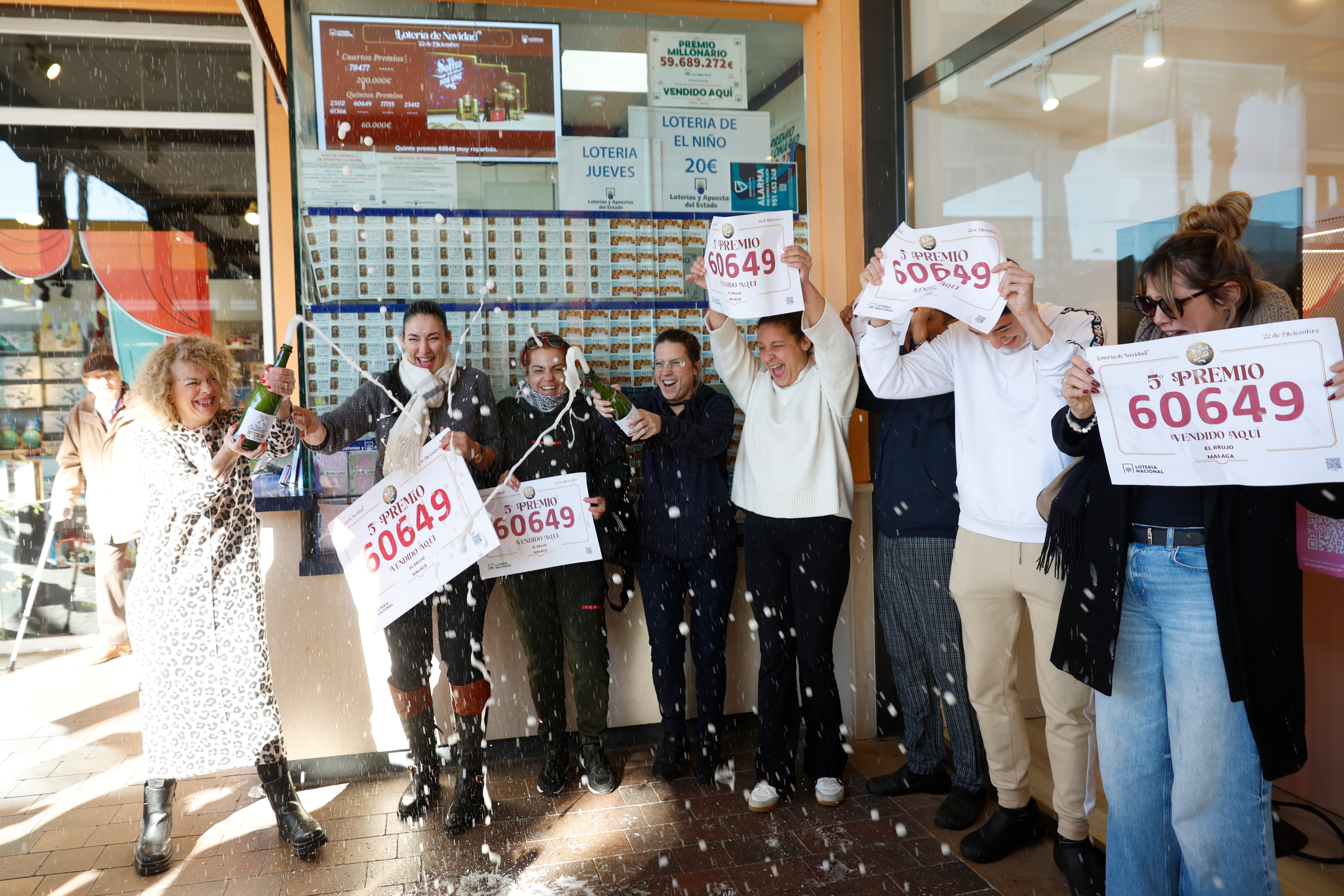 Trabajadores del Centro Comercial Plaza Mayor celebran junto a la administración número 76 de Málaga donde ha sido vendido el número 60.649, agraciado con un quinto premio en el Sorteo Extraordinario de Lotería de Navidad.