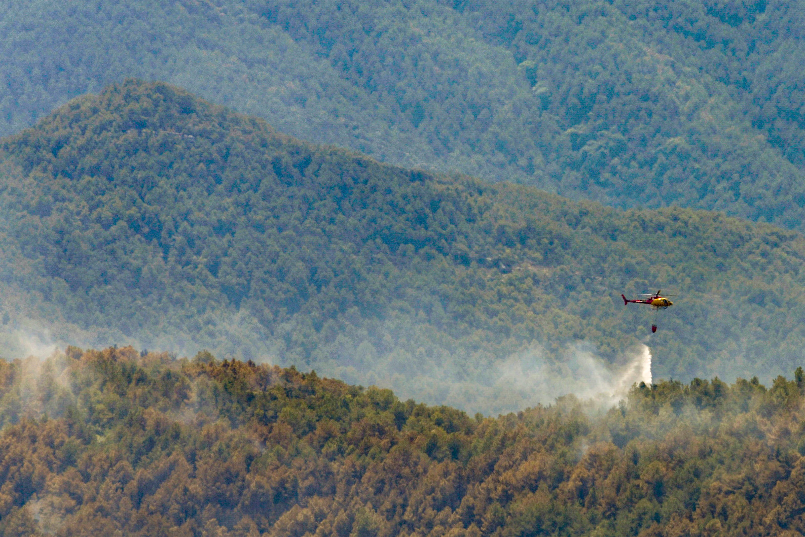 Un helicóptero de los bomberos de la Generalitat, suelta agua en el incendio de LLadurs.