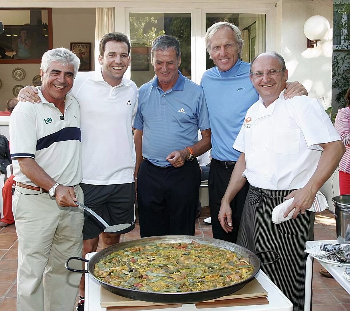 Juan Quirós disfrutando entre amigos de un arroz. El segundo por la derecha es el jugador Greg Norman.