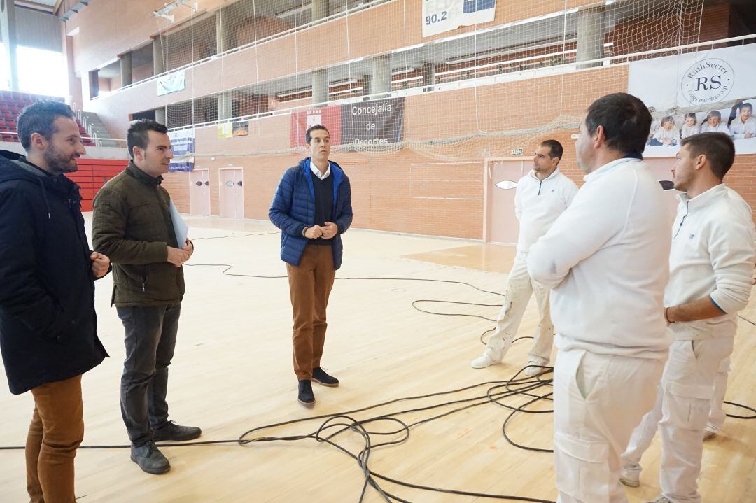 El alcalde, el concejal de Deportes y el técnico del área conversan con los operarios de la empresa encargado del lijado del parqué en el Pabellón de Elda