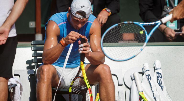 Rafael Nadal se afana en cambiar el puño de su raqueta durante un entrenamiento