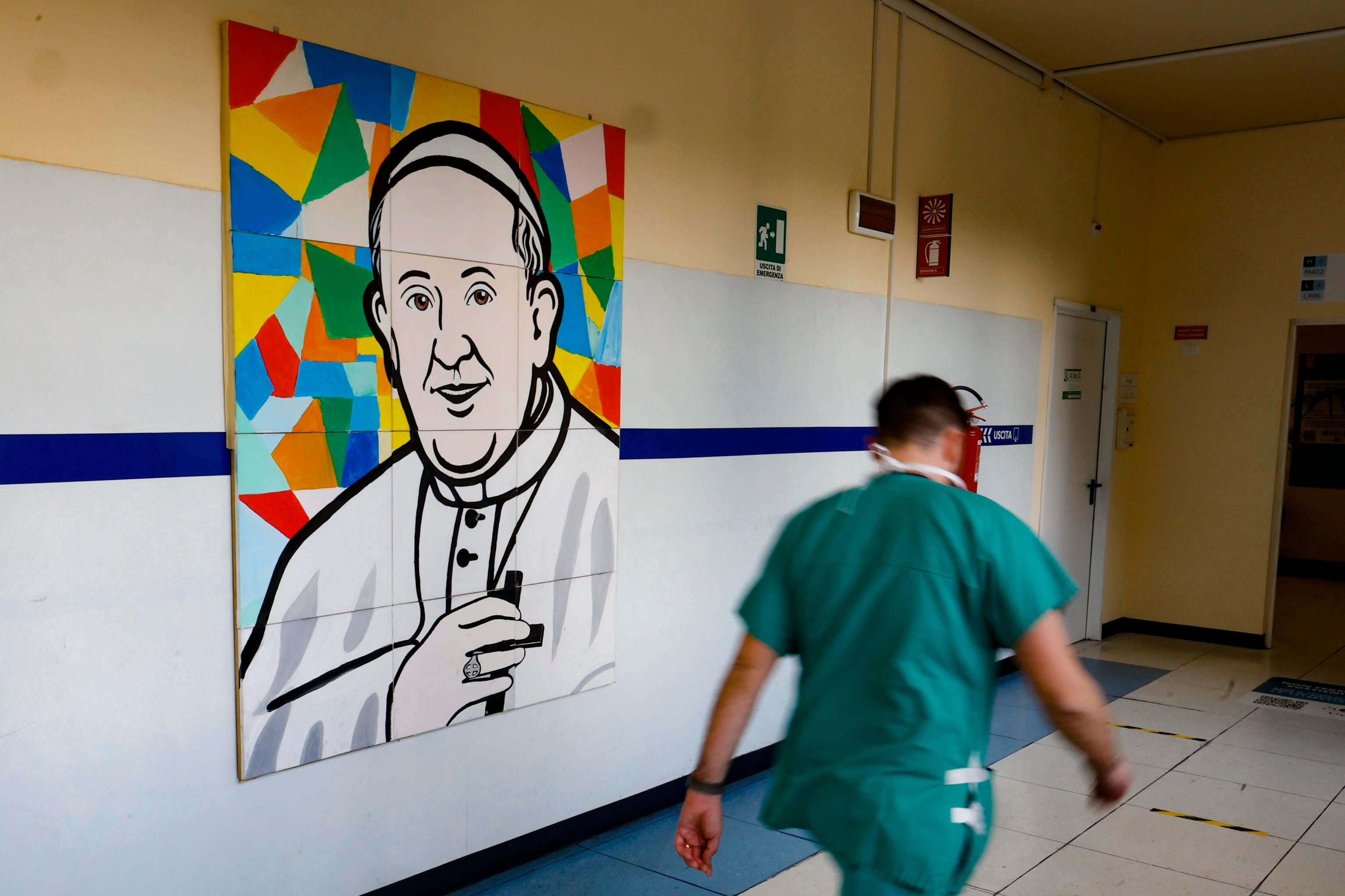 Un doctor pasa por el mural dedicado al papa Francisco en el Hospital Gemelli de Roma