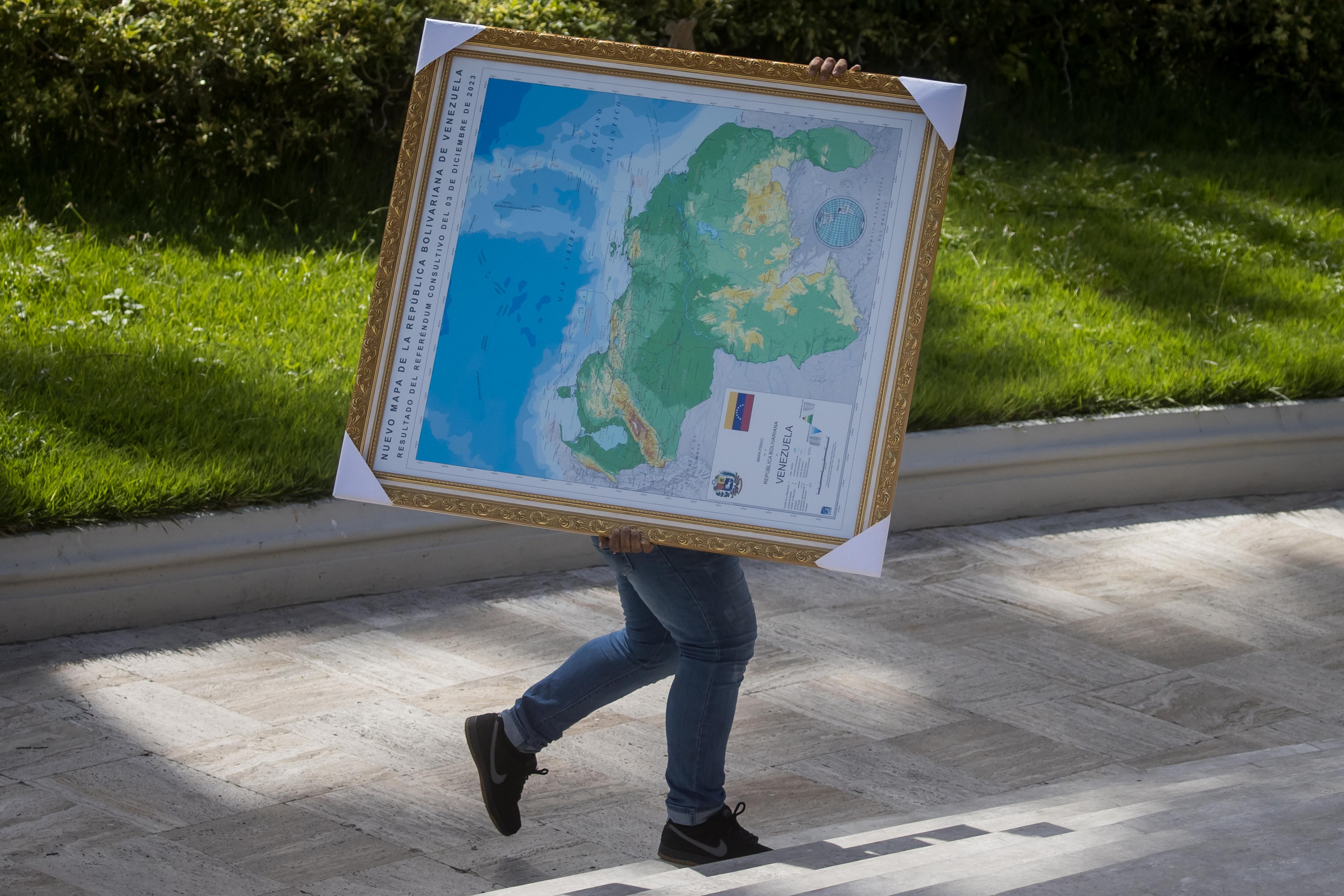 Un hombre carga hoy un cuadro del mapa de Venezuela con la adhesión del Esequibo, en uno de los jardines del Palacio Federal Legislativo en Caracas (Venezuela).