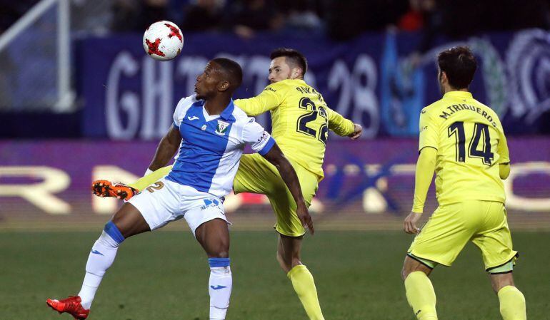 El delantero del Leganés, Beauvue (i), lucha por el balón ante el defensa del Villarreal, Rukavina (c) y el centrocampista, M. Trigueros (d), durante el partido de Ida de los octavos de la Copa del Rey de fútbol, disputado en el estadio de Butarque, en Le