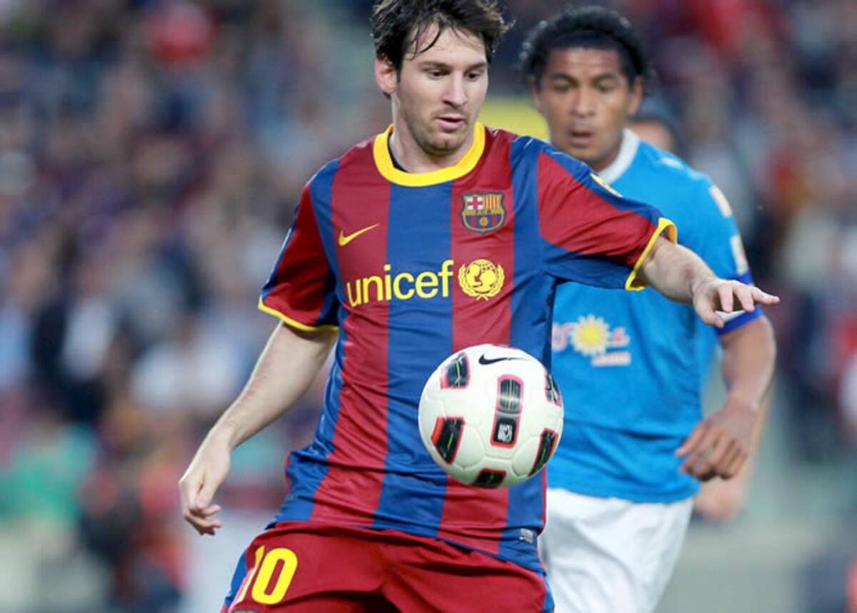 El delantero argentino del F.C. Barcelona Lionel Messi pelea un balón con el defensa peruano de la U.D Almería, Santiago Acasiete, durante el partido correspondiente a la trigésima primera jornada de Liga
