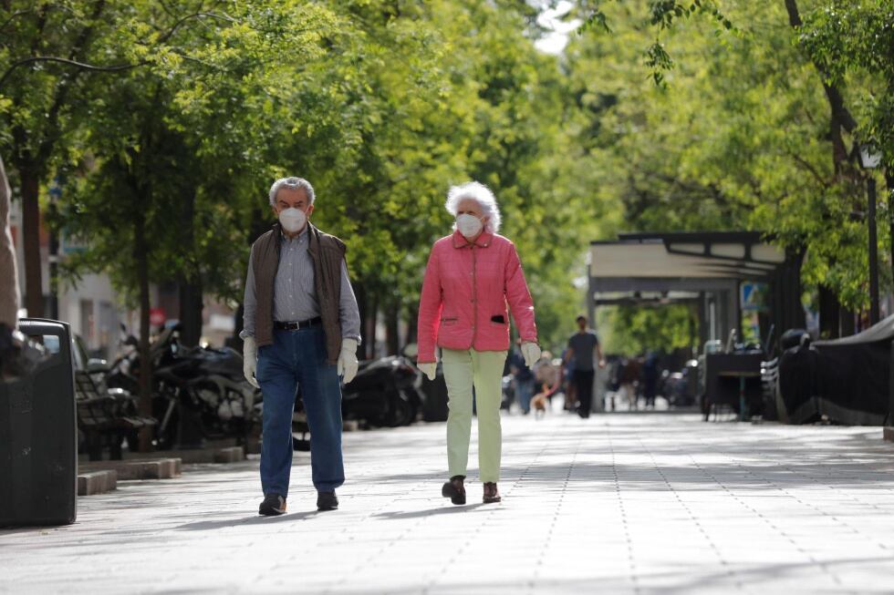 Un hombre y una mujer caminan por un céntrico paseo de Madrid en la mañana de este sábado.