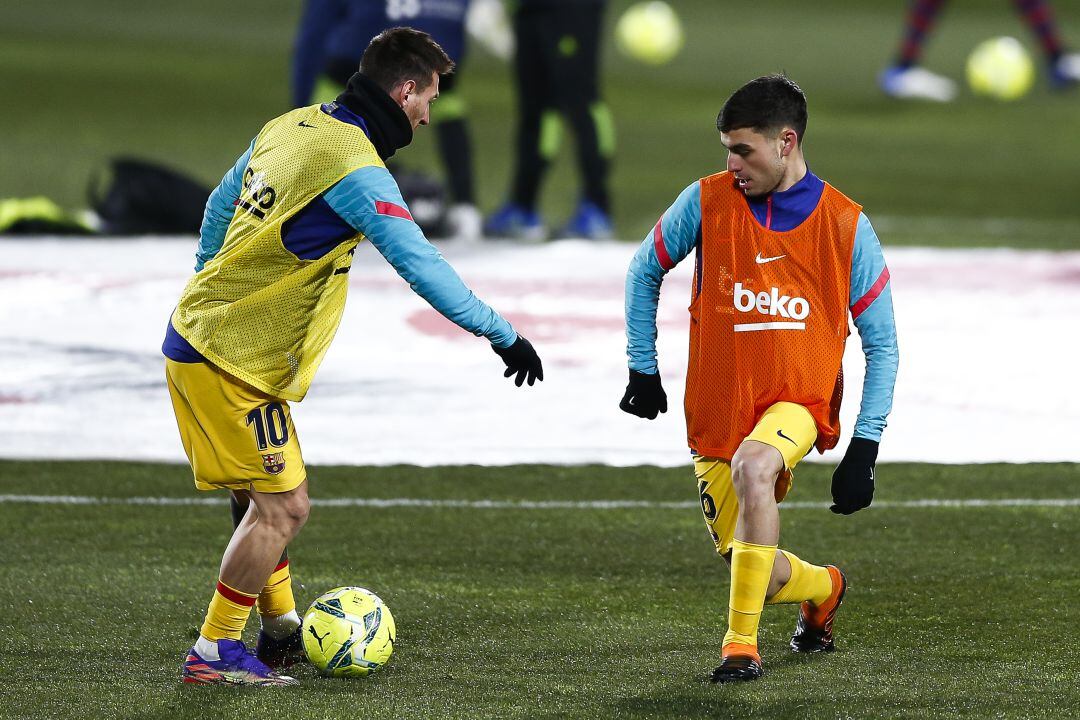 Pedri escalfant al costat de Leo Messi.