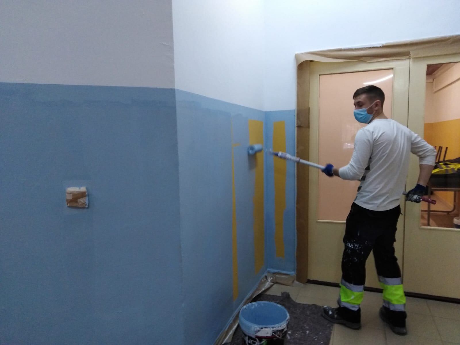 Un operario da una mano de pintura a la pared de un colegio público de Jaén