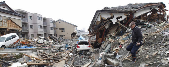 Un hombre camina en el área debastada por el terremoto y el tsunami en Kesennuma (Miyagi)