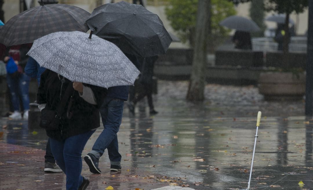 Personas se protegen de la lluvia durante una borrasca.