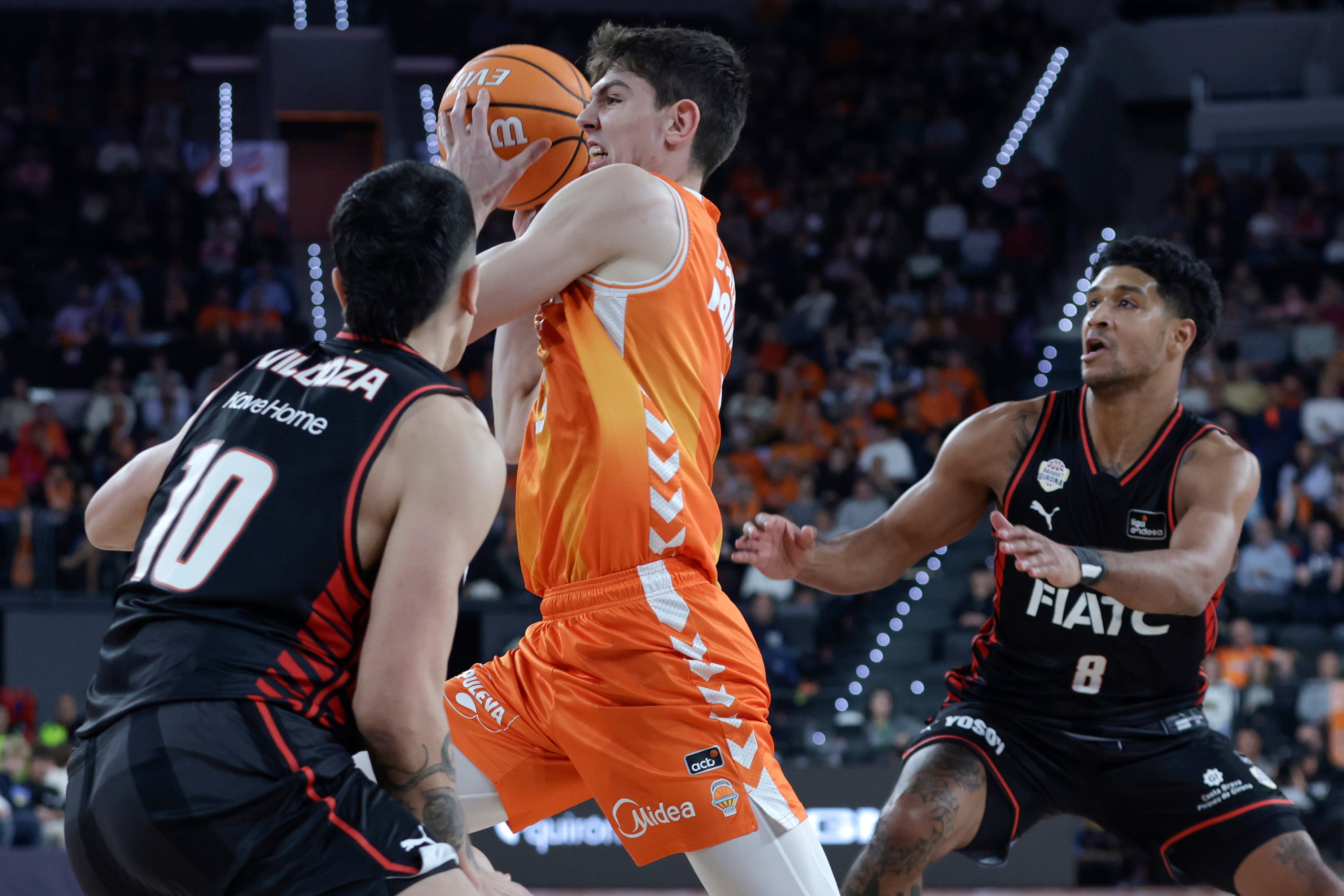VALENCIA, 23/11/2025.- El jugador del Valencia Sergio de Larrea (c) ante Pepe Vildoza (i) y Mark Hugues, del Bàsquet Girona, durante el partido de baloncesto correspondiente a la J8 de la Liga Endesa, disputado hoy domingo en el pabellón Roig Arena de Valencia, entre Valencia Basket y Bàsquet Girona. EFE/ Miguel Ángel Polo
