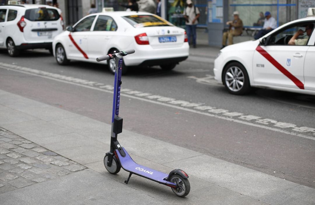 Un patinete eléctrico aparcado frente a unos taxis en las inmediaciones de la Puerta del Sol de Madrid.