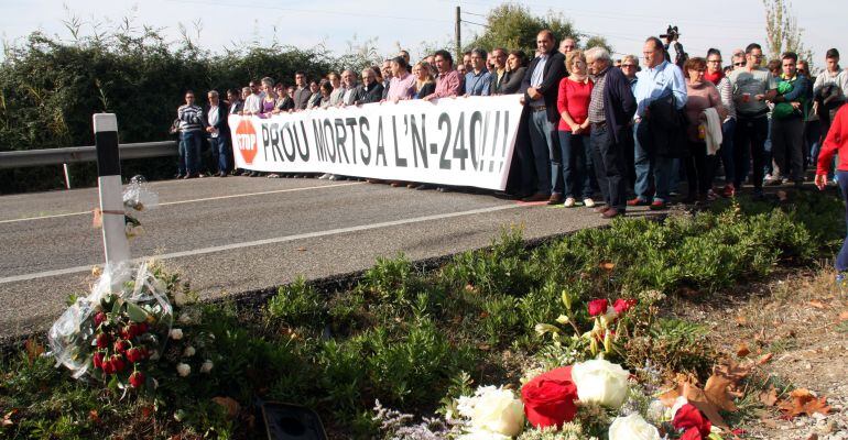 Imatge dels concentrats tallant la carretera N-240 al punt de l&#039;últim accident mortal amb rams de flors en primer terme.