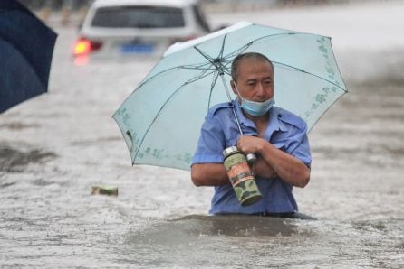 Una persona con un paraguas avanza por la calle con medio cuerpo sumergido en el agua.