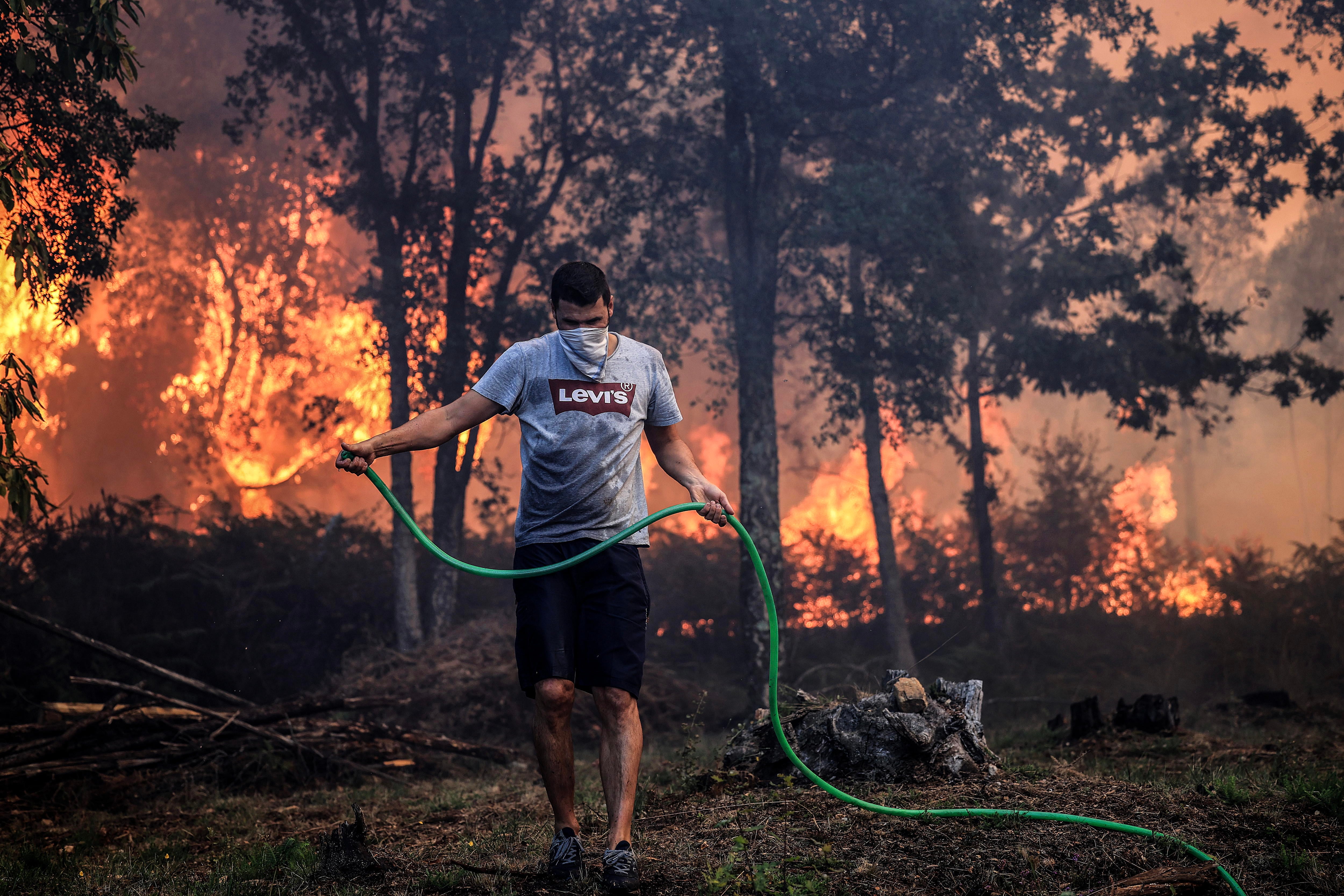 Un joven intentando sofocar el fuego en Oliveira de Azemeis, Agueda, Portugal