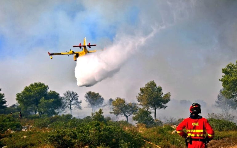 Pla general. Un avió descarrega aigua a l&#039;incendi de Benitatxell. Horitzontal. 