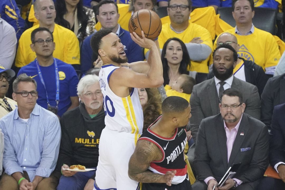 Stephen Curry intenta lanzar, pero Damian Lillard realiza una falta personal al intentar defender