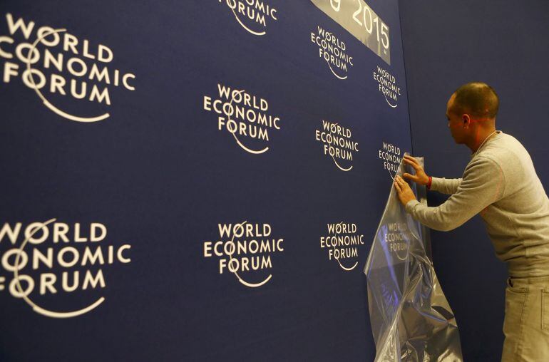 A worker sets up logos of the World Economic Forum (WEF) at the congress center in the Swiss mountain resort of Davos January 20, 2015. More than 1,500 business leaders and 40 heads of state or government will attend the January 21-24 meeting of the WEF t