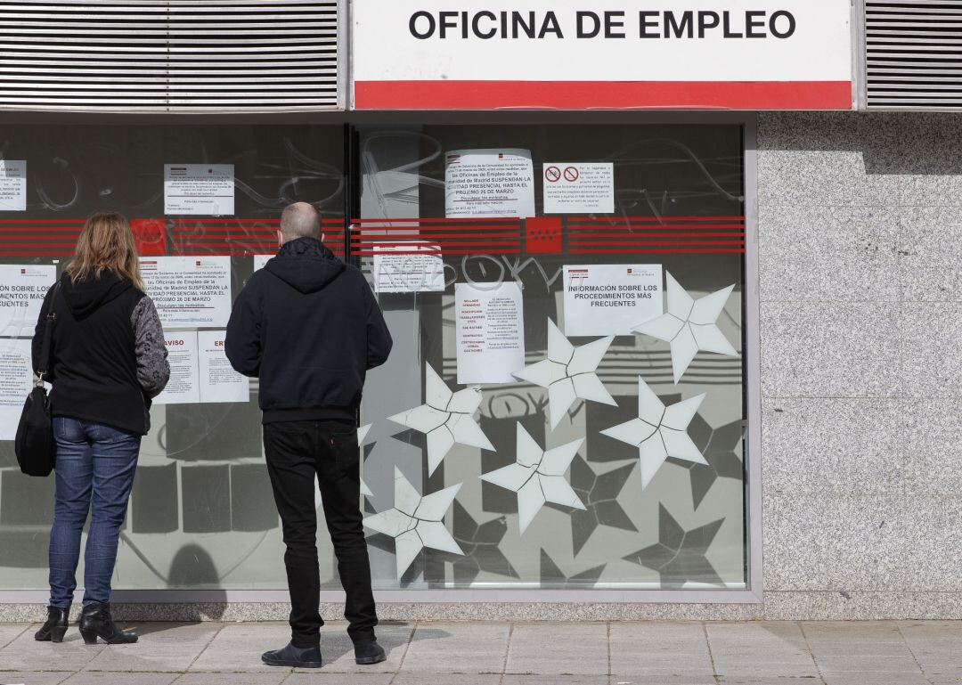 Dos personas leen los carteles de una oficina de empleo