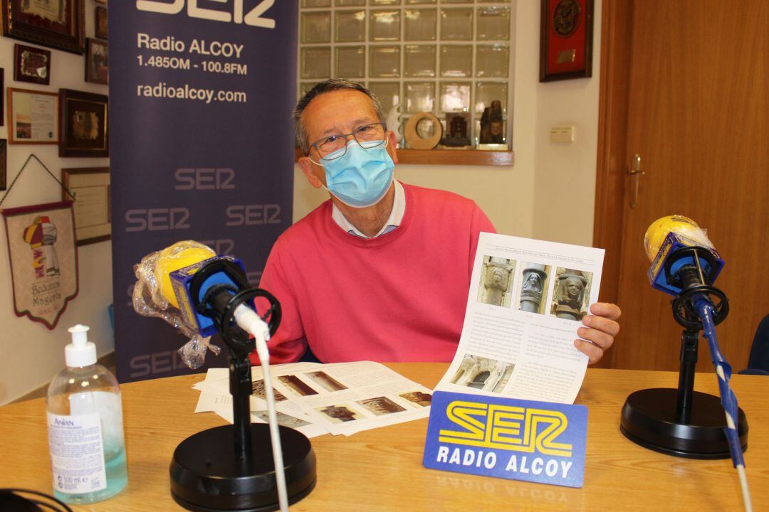 José María Segura, en el estudio de Radio Alcoy, mostrando las hojas de su estudio sobre estos rostros realizados en hierro en la parte alta de los tubos de los desagües de las casas
