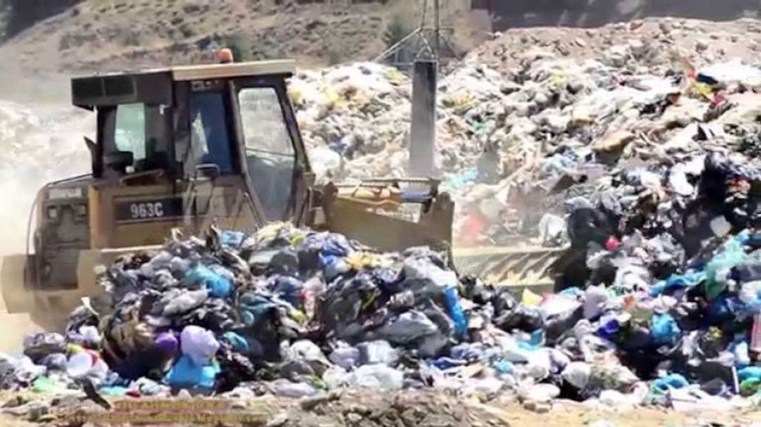 Una máquina excavadora apila varias bolsas de basura en el vertedero de Alcalá de Henares.