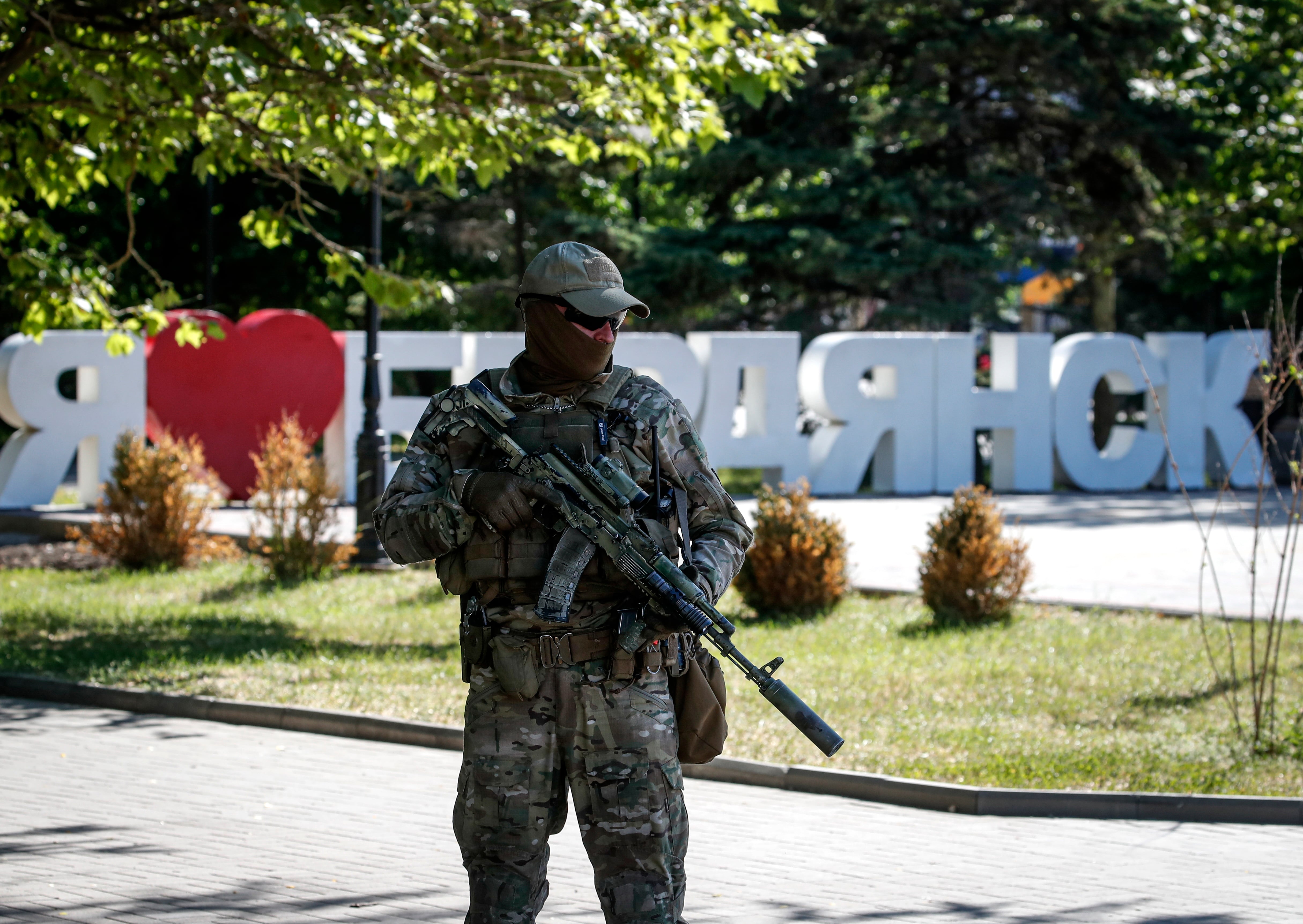 Un militar ruso vigila frente a un cartel que dice &#039;Me encanta Berdyansk&#039;, una ciudad que está ubicada en el territorio controlado por las tropas de la Federación Rusa