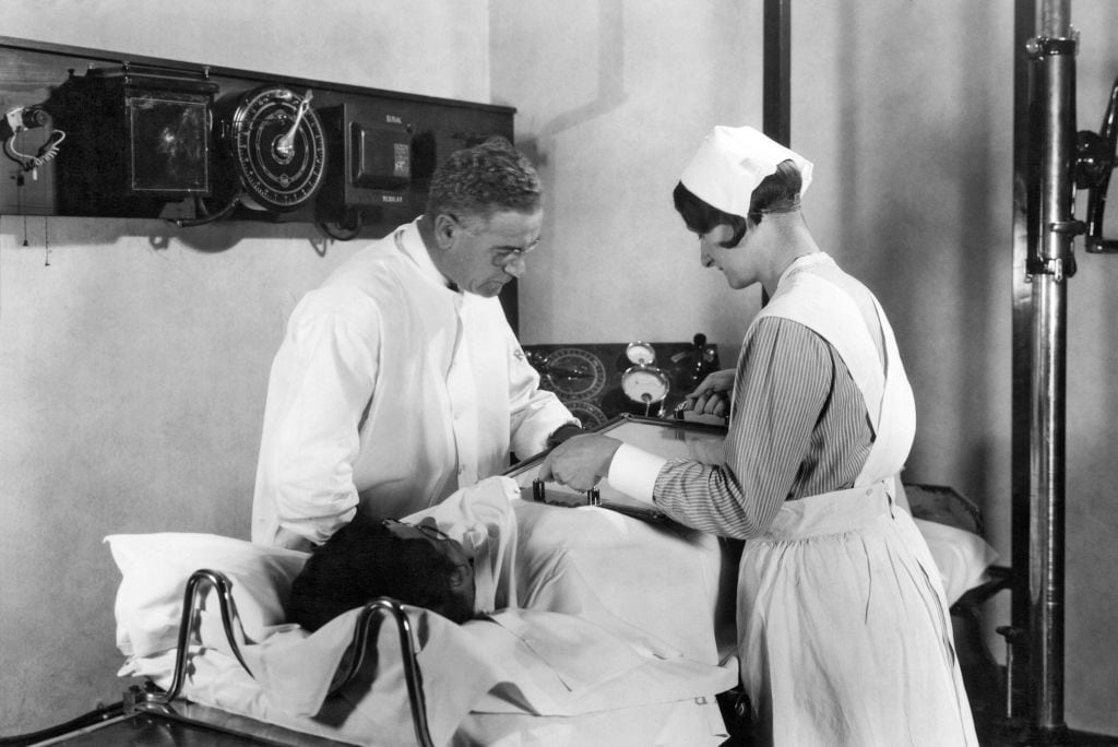 A doctor and nurse performing a fluoroscopic examination of the stomach during the Barium Meal X-Ray Examination at John Harvey Kellogg&#039;s Battle Creek Sanitarium, Battle Creek, Michigan, circa 1928. (Photo by Underwood Archives/Getty Images)