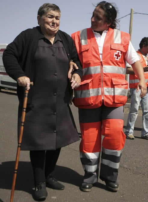 Una vecina de La Restinga, en la isla de El Hierro, es acompañada por un miembro de Cruz Roja durante la evacuación de la localidad