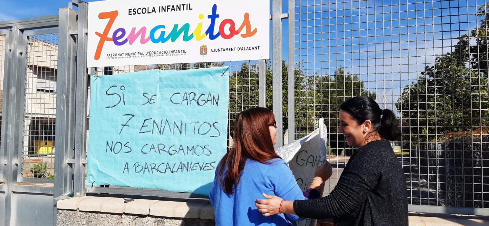 Dos madres colocan una pancarta en la puerta de la Escuela Infantil Municipal 7 Enanitos