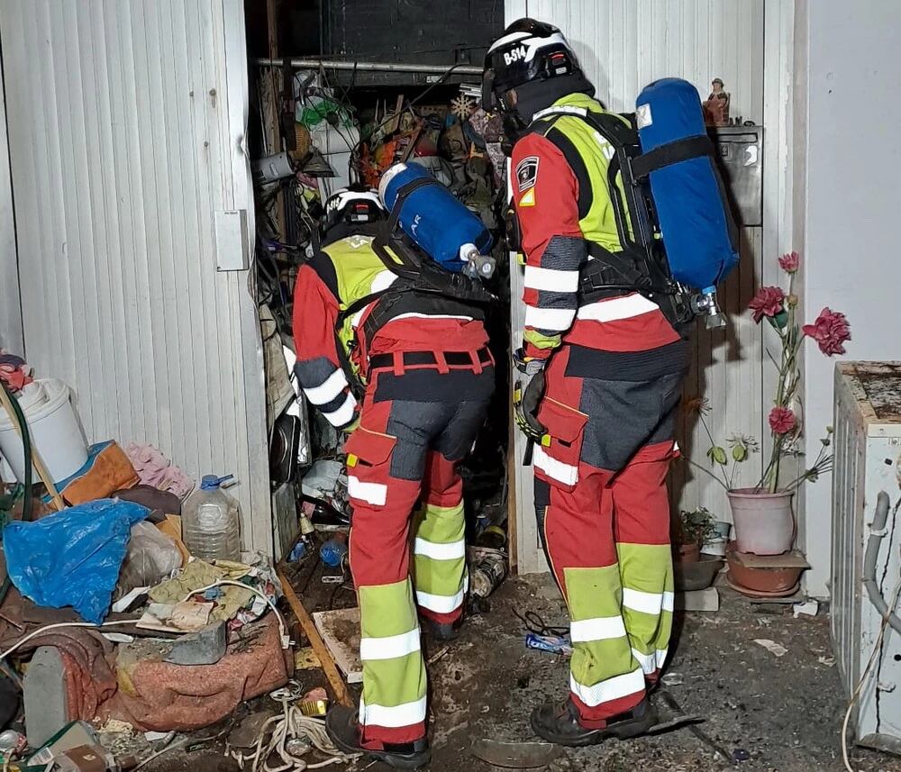 Los bomberos rescatando el cuerpo de un hombre de 73 años fallecido bajo un montón de basura en San Bartolomé.