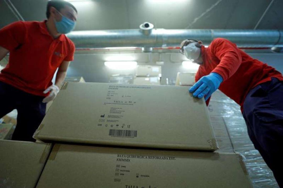Operarios desembalan el material sanitario (guantes, mascarillas y monos de protección) llegado de China. 