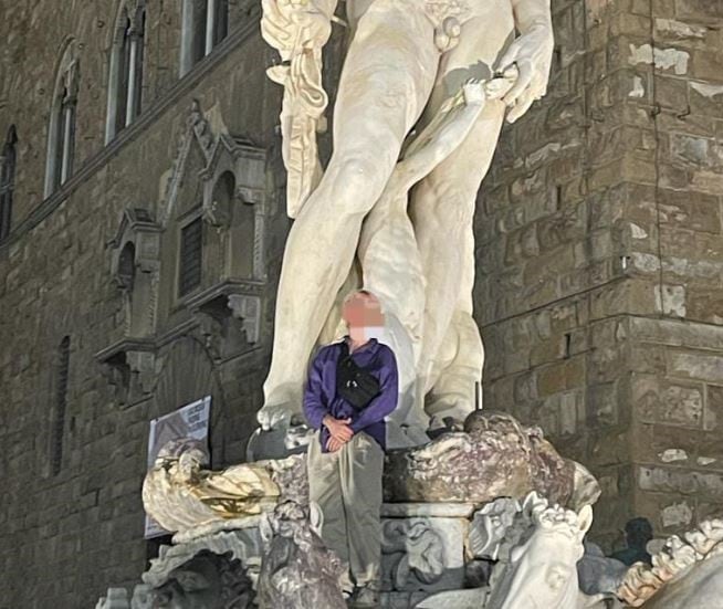 Un turista subido a la estatua de Neptuno en Florencia