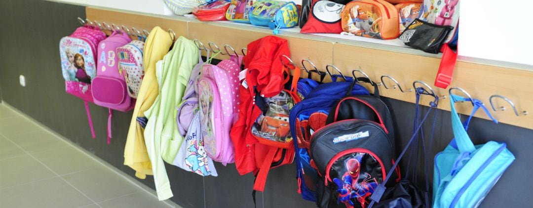 Mochilas en los percheros de un colegio