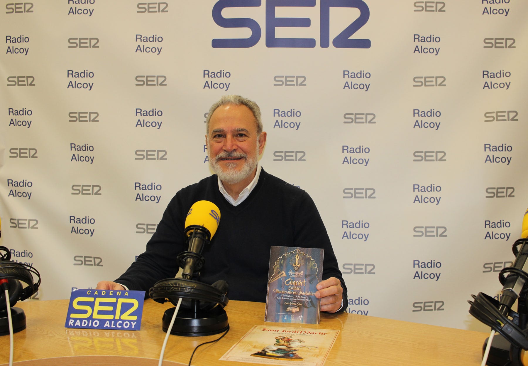 Indalecio Carbonell, en el estudio central de Radio Alcoy con un programa de mano del concierto y con una concordia de la Asociación de San Jorge con la imagen de un San Jorge heredado de su abuelo