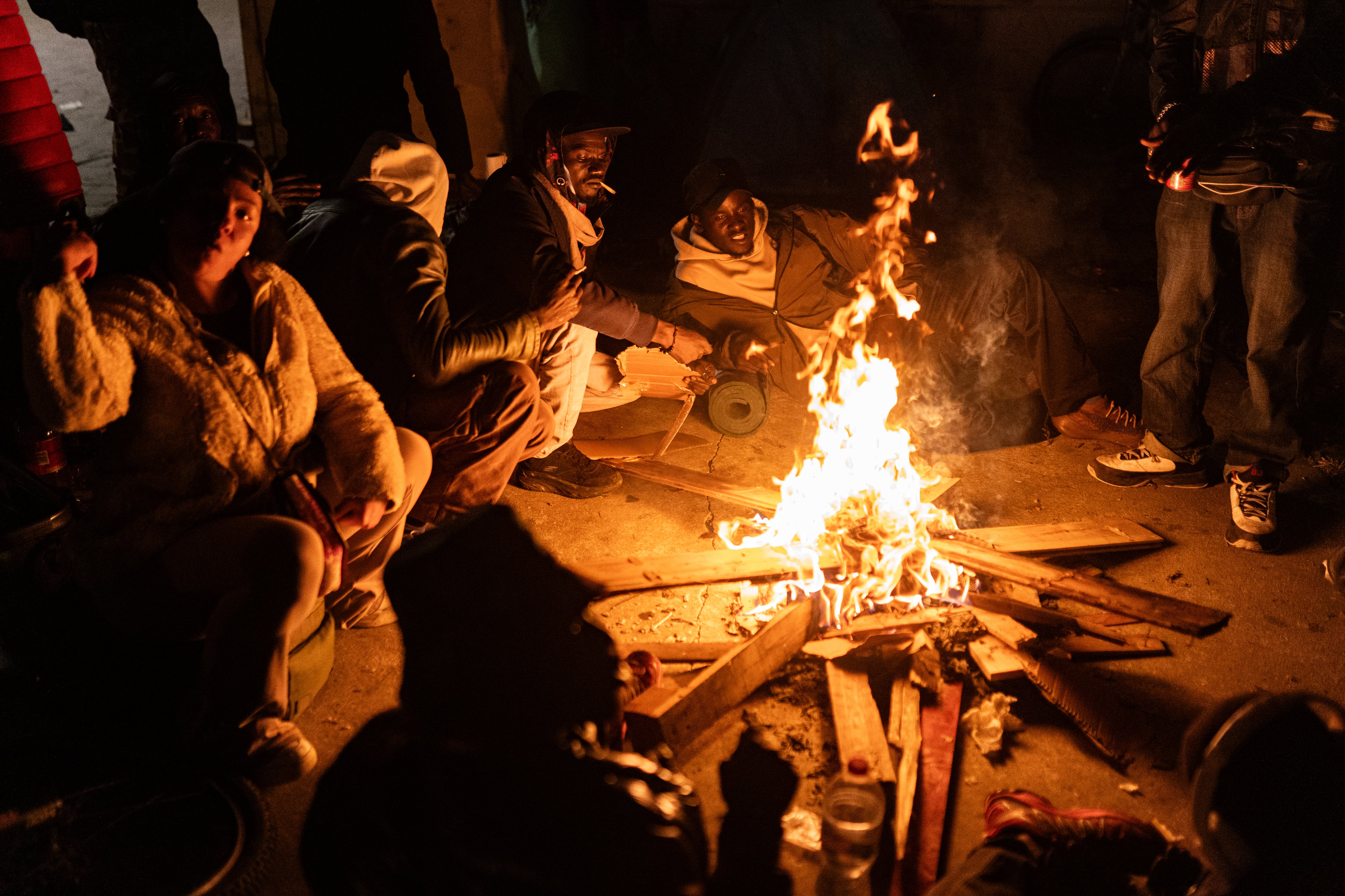 Personas reunidas alrededor de una hoguera durante la noche, en el marco del desahucio ocurrido en Badalona.