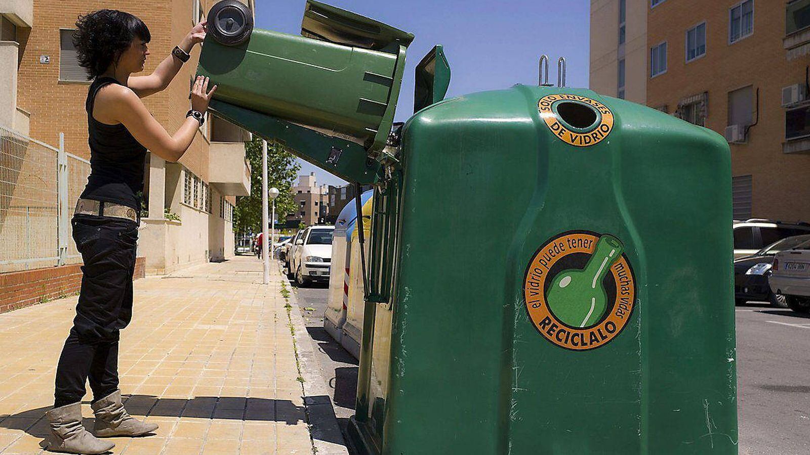 Una mujer recicla vidrio en un contenedor.