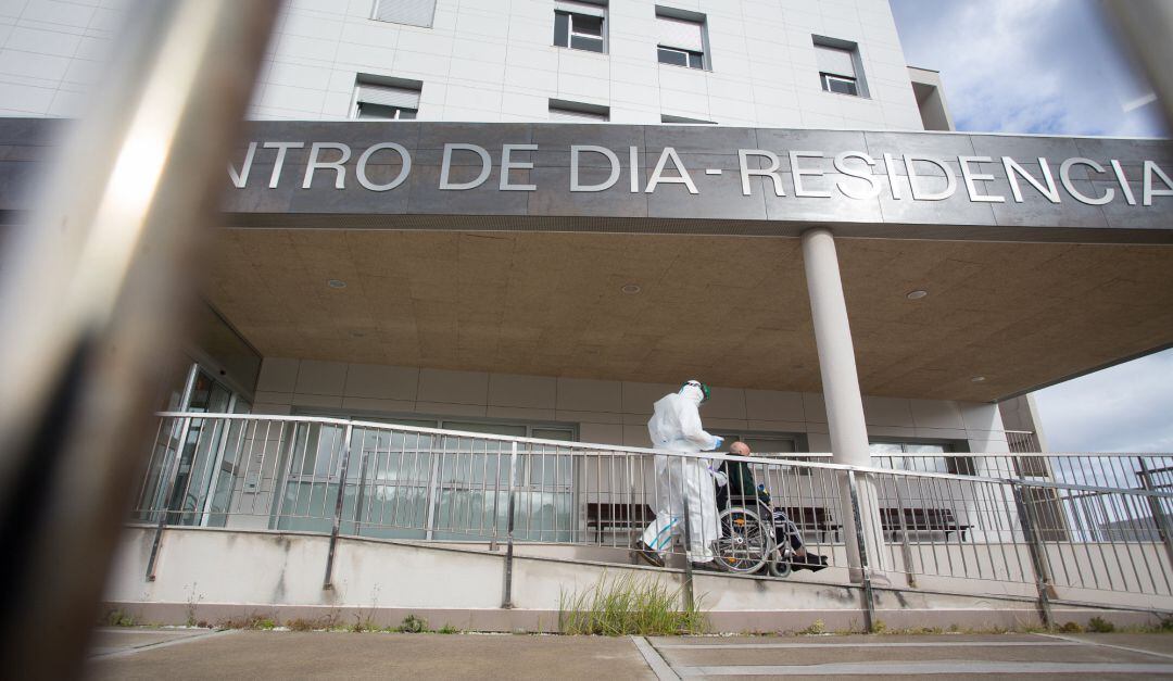 Un trabajador sanitario totalmente protegido acuden a buscar a un anciano de la residencia de ancianos